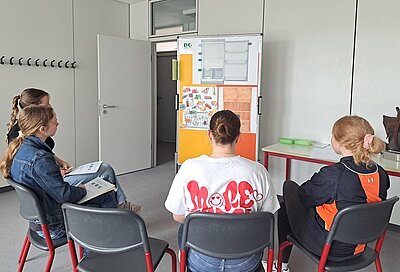 Die angehenden Sozialassistentinnen der Euro Akademie Magdeburg sitzen in einem Halbkreis vor einem Flipchart.
