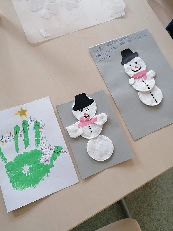 Engagiert und kreativ Selbst gebastelte Weihnachtskarte der Grundschüler mit aufgedruckter Hand und Schnemannmotiv.