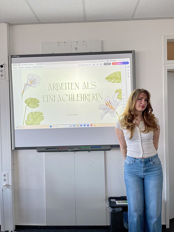 Eine junge Frau steht vor einem digitalen Whiteboard mit einer Präsentationsfolie zu einem Berufsthema.