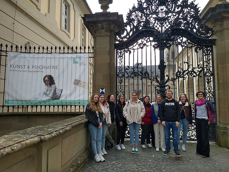 Aufklärung durch Kunst Die Auszubildenden posieren vor dem großen Eingangstor zur psychiatrischen Klinik für ein Gruppenfoto.