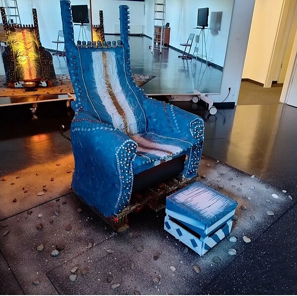 Exponat des blauen Throns mit passendem Hocker, die beide mit unterschiedlichen Materialien und Perlen verziert sind..