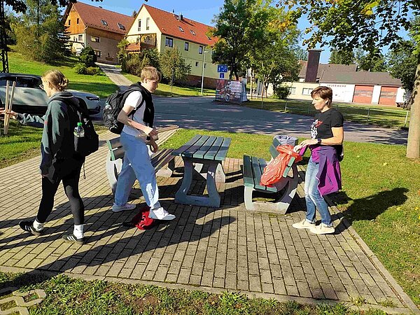 Schülerinnen und Schüler räumen mit Mülltüten und Müllzangen ausgestattet auf.