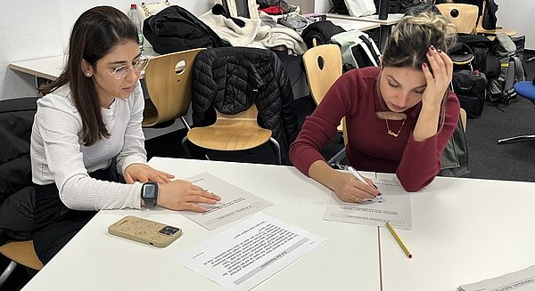 Facharbeitstag in Würzburg Zwei weibliche Auszubildende sitzen am Tisch und sind vertieft in ihre Facharbeiten.