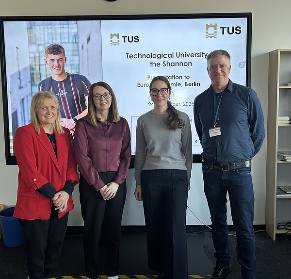 Foto von drei Frauen und einem Mann, die lächelnd vor einer Präsentation der TUS Technological University of the Shannon stehen