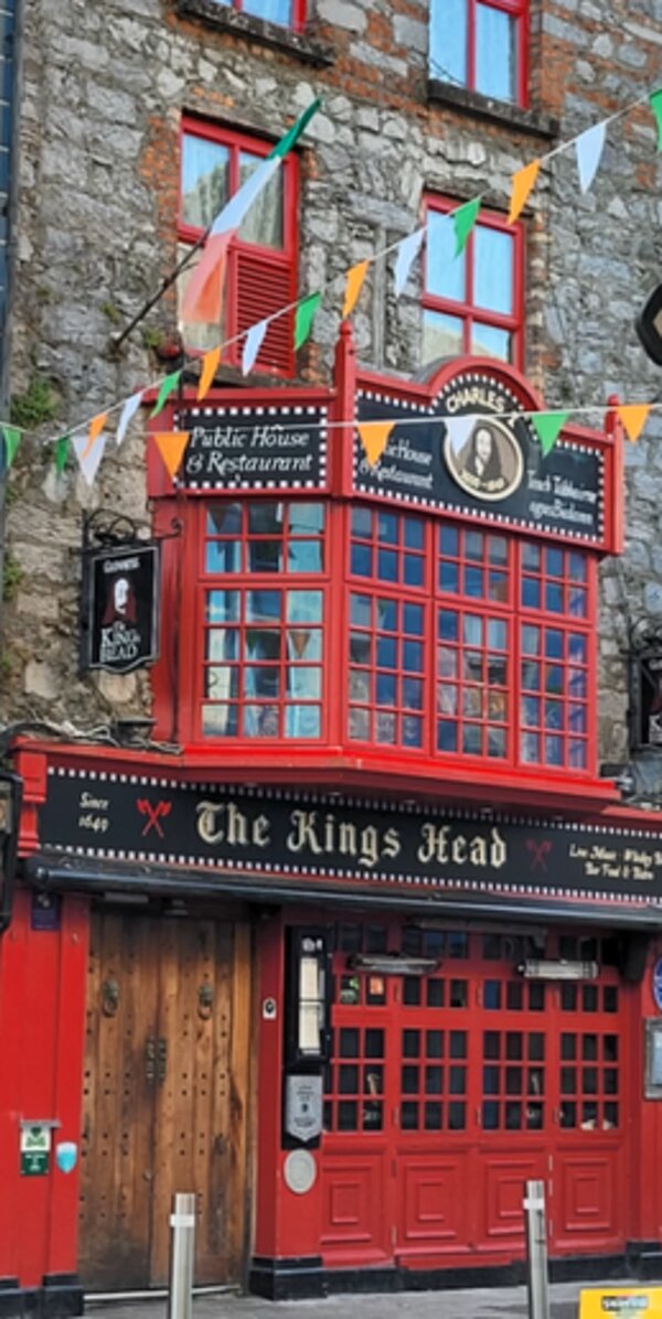 Ein typischer rot lackierter irischer Pub in der Küstenstadt Galway ist zu sehen mit vielen Fahnen über den Fenstern angebracht.
