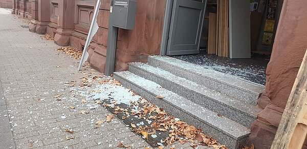Treppenstufen, die bedeckt sind mit Scherben einer zerbrochenen Glastür.