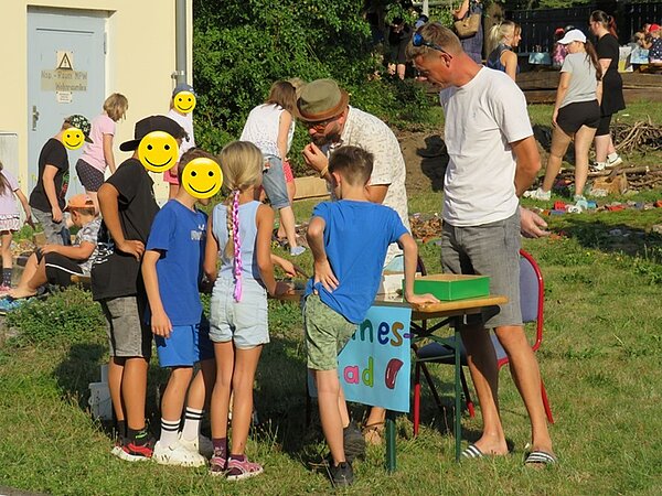 Interessierte Kinder und Erwachsene stehen vor einer Mitmach-Station zum Sinne erforschen.