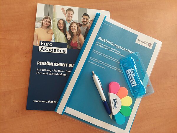 Ausbildungsstart an der Euro Akademie Jena Zwei Prospekte der Euro Akademie liegen auf einem Holztisch.
