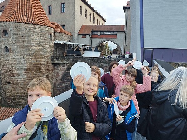 Kultur- und Bildungsreise in die Toskana Thüringens Kinder sind auf einem Ausflug und zeigen Porzellanteller in die Kamera.