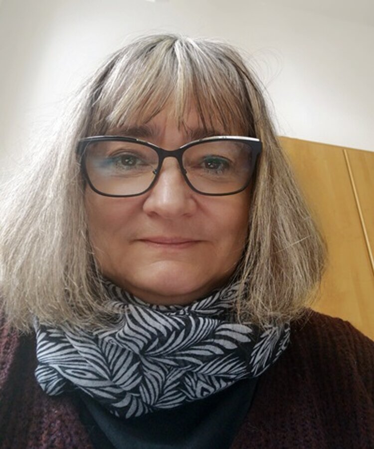 30 Jahre Ausbildung im Fachbereich Physiotherapie Mitarbeiterin der Euro Akademie Halle Astrid Jammermann lächelt in die Kamera, trägt einen schwarz weißen Loop-Schaal, eine Brille und einen Longbob mit Pony.