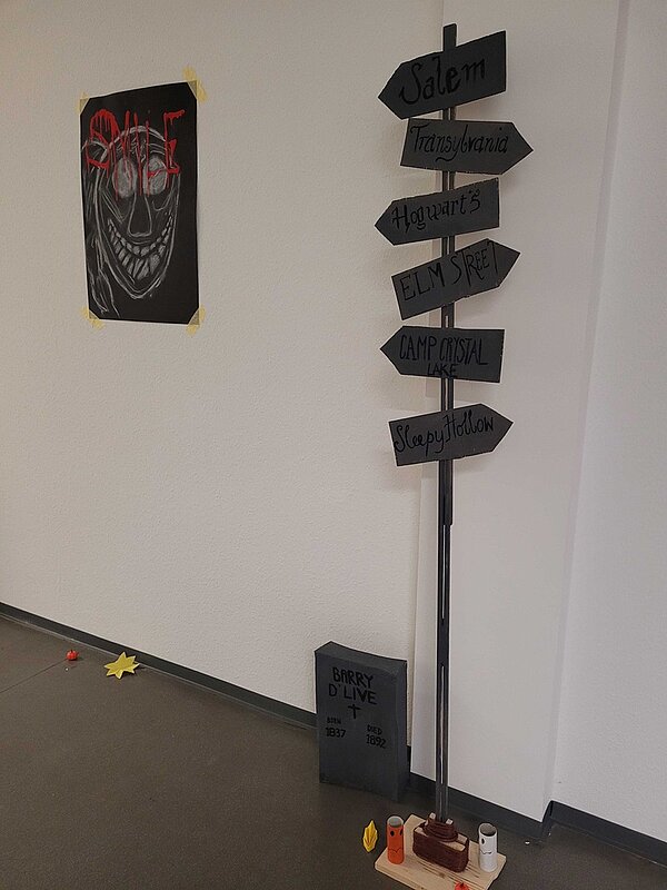 Gruseliger Wegweiser, der in verschiedene Richtungen zeigt, mit Grabstein und spooky Bild.