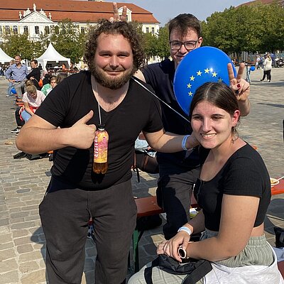 Eine junge Frau und ein junger Mann posieren vor einer Kamera mit der Mann macht seinen Daumen nach oben.