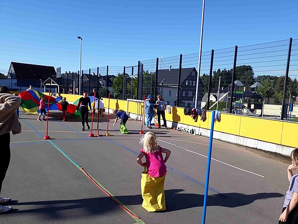 Kinder beim Sackhüpfen auf dem Sportplatz messen sich miteinander.