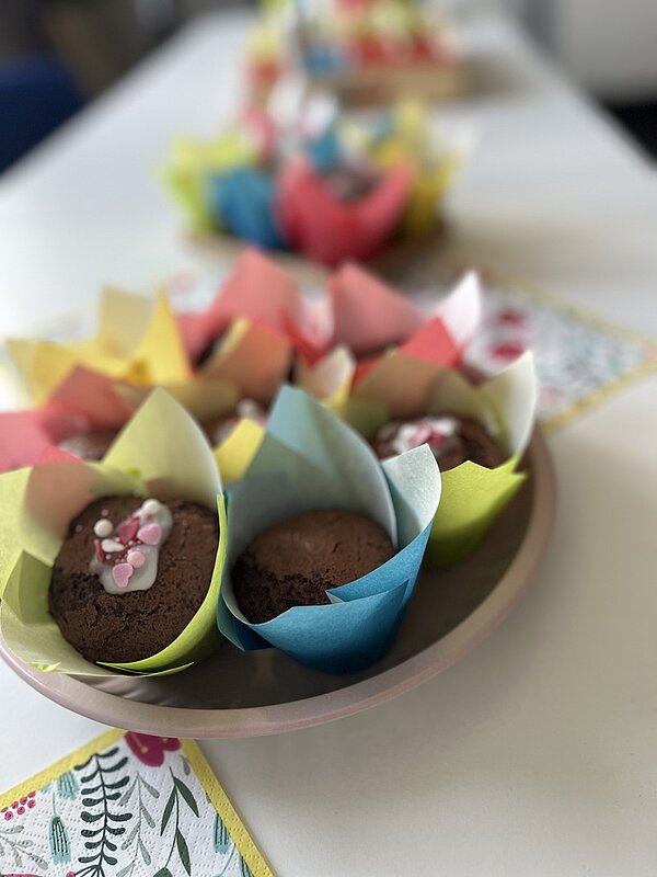 Tag der offenen Tür Auf dem Tisch lieben auf Tellern schön angerichtete Schokoladenmuffins mit buntem Papier umwickelt.