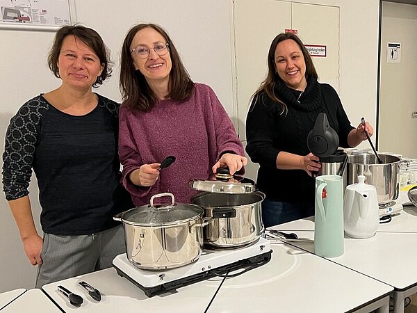 Drei Frauen stehen hinter den Tischen, auf denen die Kochtöpfe auf Warmhalteplatten thronen: Links die Würstchen, rechts der Kinderpunsch.