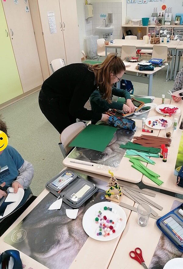 Engagiert und kreativ Auszubildende unterstützt Schüler beim Basteln.
