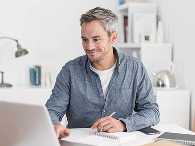 Auf dem Bild arbeitet eine Person an einem Laptop in einem hellen Raum.