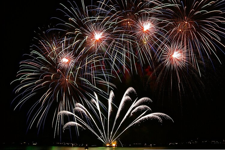 Auf ein tolles neues Jahr! In einem Nachthimmel explodieren mehrere Silvesterraketen.