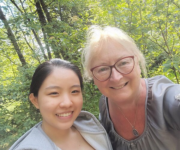 Ehrenurkunde für Ramona Wagner Selfie von einer blonden Frau mit dunkelroter Brille und eine silbernen Kette zusammen mit einem jungem Mädchen mit dunklen Haaren und Trainingsjacke in einem lichtdurchfluteten Wald.