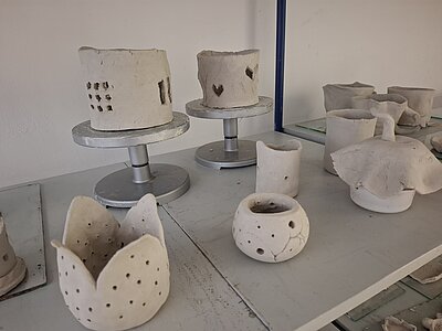 Ein Regal mit verschiedenen unglasierten Tonkunstwerken.