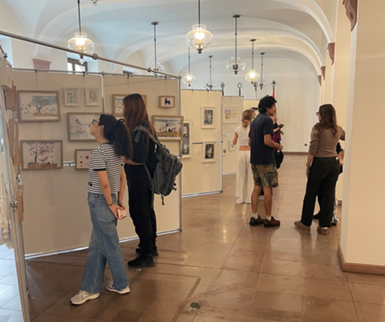 Mehrere Jugendliche besuchen eine Ausstellung und schauen sich die Bilder an den Wänden an.