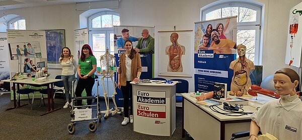 Mehrere Ausstellerinnen der Euro Akademie und Partner wie die Volkssolidarität stehen an Info-Ständen. Anatomische Modelle und Roll-ups verdeutlichen den Fokus auf Pflege- und Sozialberufe.