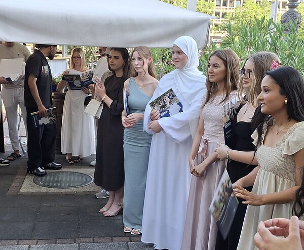 Gruppe von Kursteilnehmenden steht mit Broschüren in der Hand im Außenbereich eines Restaurants.