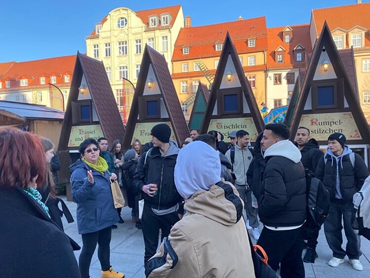 Schüler stehen vor Verkaufsbuden auf dem Weihnachtsmarkt in Weißenfels.