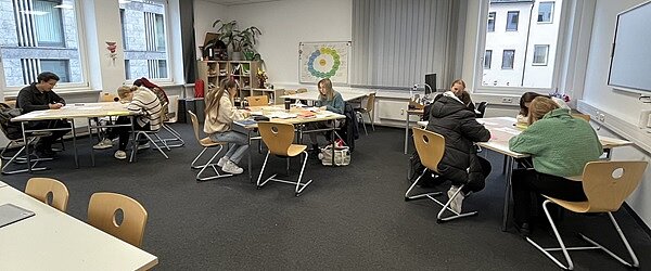 Facharbeitstag in Würzburg Auszubildende sitzen im hellen Klassenraum an Tischen und erarbeiten ihre Facharbeit.