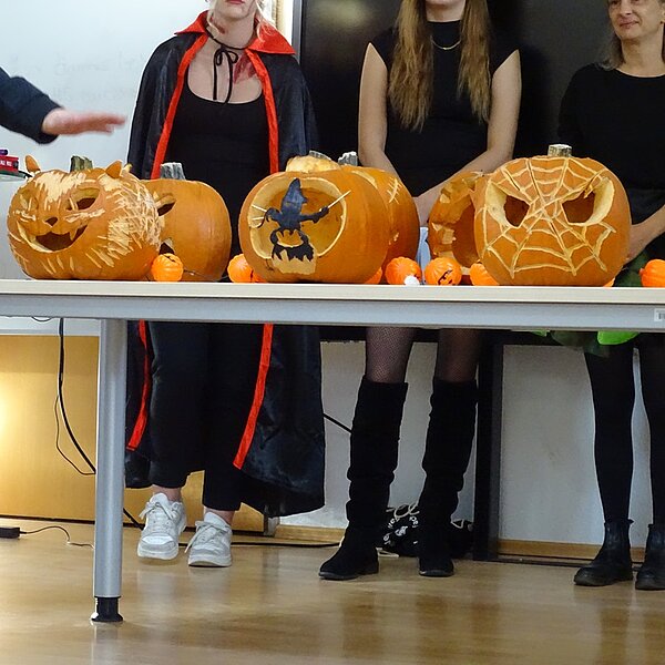 Happy Halloween! Kreativ geschnitzte Halloween-Kürbisse auf einem Tisch.