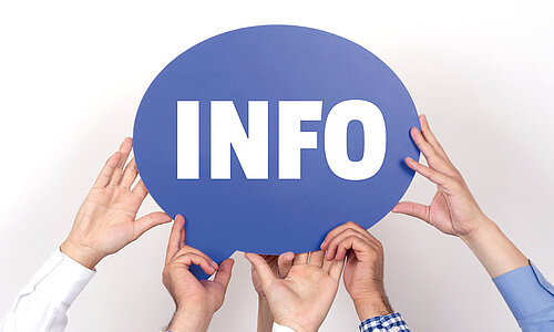 Mehrere Hände halten ein blaues Schild mit der Aufschrift "Info" in großen weißen Lettern hoch. 