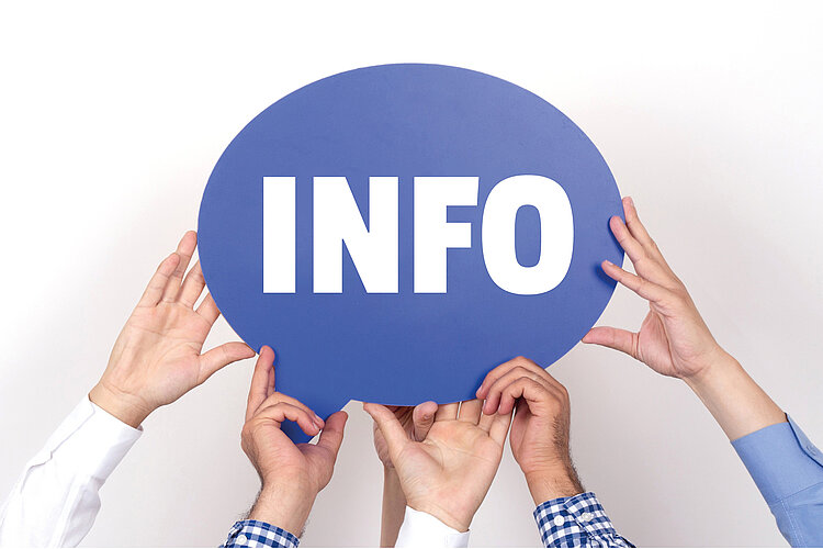 Mehrere Hände halten ein blaues Schild mit der Aufschrift "Info" in großen weißen Lettern hoch. 