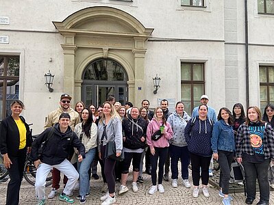 Die rund 25 weiblichen und männlichen Auszubildenden zu Pflegefachkräften an der Euro Akademie Jena  stehen vor dem Eingang des Universitätsklinikums Jena und posieren lächelnd für ein Gruppenbild, bevor sie hineingehen, um sich die Anatomische Sammlung anzusehen. 