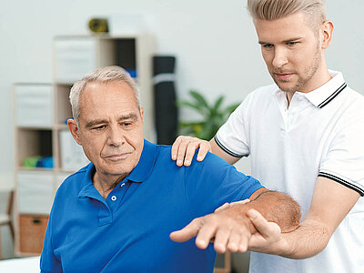 Auf dem Bild ist ein Physiotherapeut, der einen älteren Patienten behandelt. Es zeigt einen Moment professioneller Gesundheitsfürsorge.