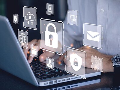 Eine Person arbeitet an einem Laptop, während verschiedene Symbole für Sicherheit und Technologie über der Tastatur schweben. Diese Symbole umfassen ein Vorhängeschloss, eine Cloud mit einem Pfeil, ein Benutzersymbol, ein Schild, einen Globus, einen Einkaufswagen, einen Briefumschlag und einen Fingerabdruck. Die Person trägt eine Armbanduhr und ein weißes Hemd.