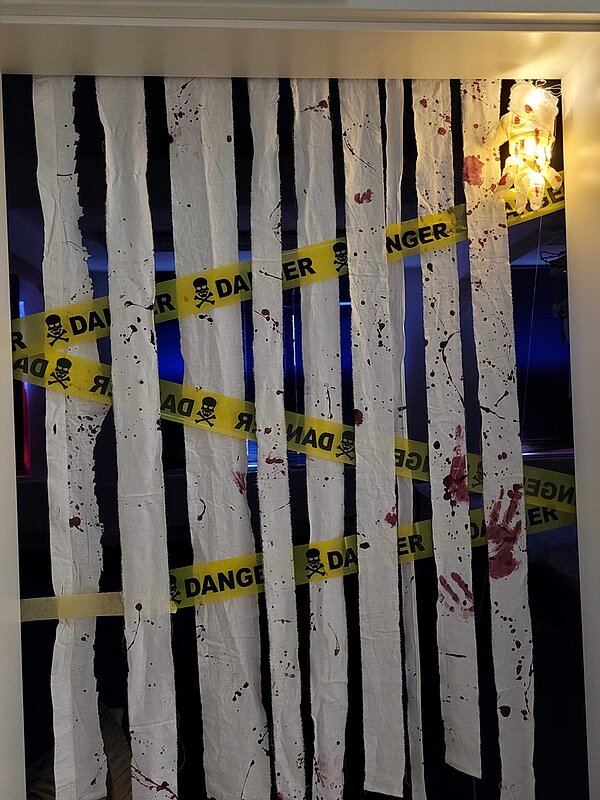 Mit Totenkopf-Absperrband und von der Tür hängenden, blutig angemalten Stofffetzen versperrte Tür.