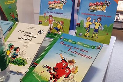 Auf einem Tisch liegen sechs verschiedenen Kinderbücher zum Thema Fußball, darunter die Titel "Rivalen auf dem Fußballplatz" und "Hat Jesus Fußball gespielt?".