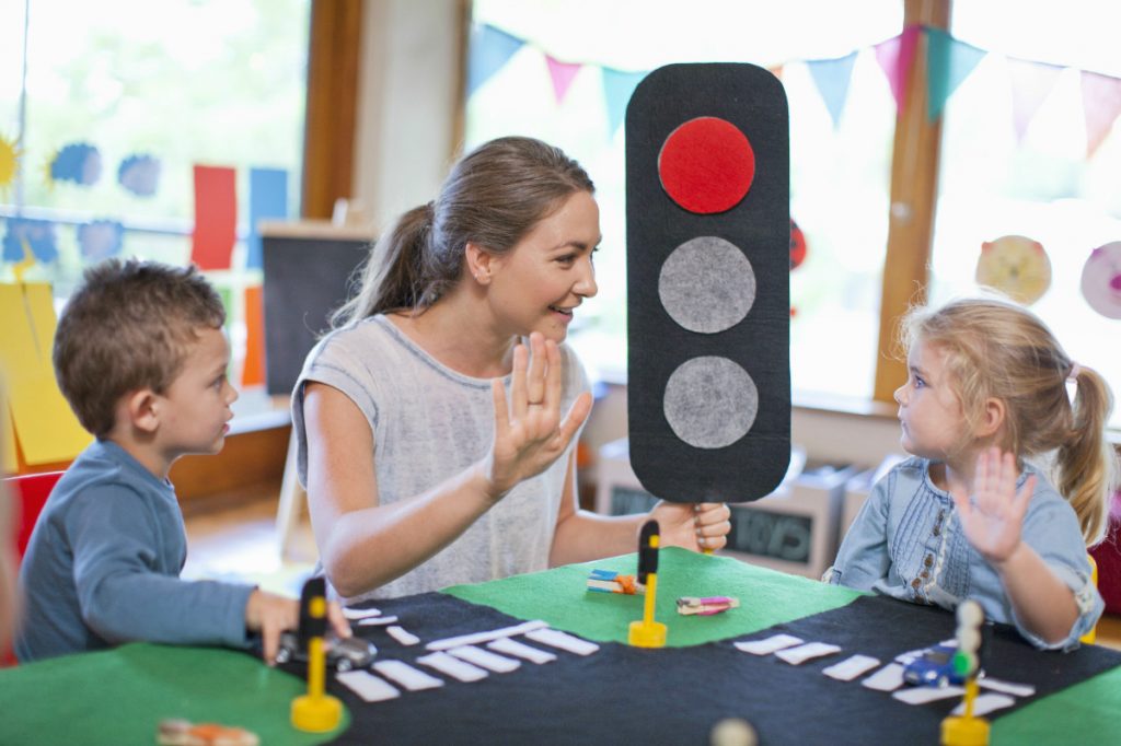 Eine Erzieherin erklärt Kindern die Bedeutung der Ampel im Kontext von Erziehungsstilen und ADHS.