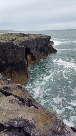 Blick von den Klippen auf die tosenden Wellen des Meeres.
